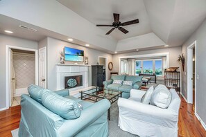 Bright living room with raised ceiling that opens to sunroom with lagoon view