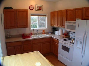 Fully equipped kitchen with a view of Palm trees, stone paths and garden