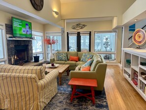 Living Room with leather sectional and oversized chair. Wood-burning fireplace.