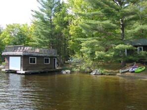 Boathouse with roof deck, dining table seats 6, and 4 lounge chairs facing lake.