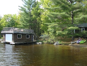 Boathouse with roof deck, dining table seats 6, and 4 lounge chairs facing lake.