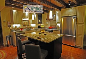 Kitchen with stainless counters, granite island, and seating for 3