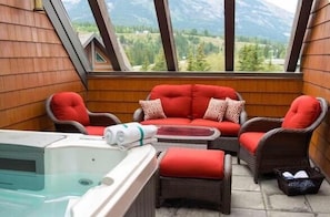 Enjoy breathtaking mountain views from the outdoor living space, complete with a six-person hot tub and comfortable outdoor furniture.