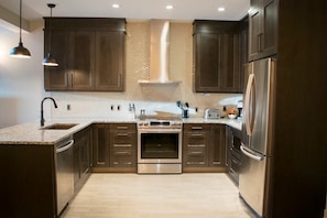 Bright and open gourmet kitchen with modern appliances, stone counters, and breakfast bar with seating. 
