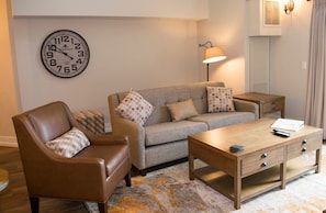 The spacious living room, with ample seating, seamlessly connects to the kitchen and dining area, offering a perfect space for relaxation and socializing.