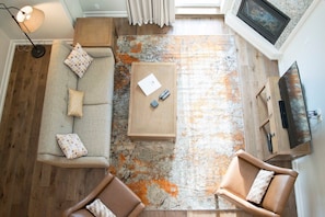 Overhead view of the living room, featuring a stunning granite fireplace and a large framed TV.