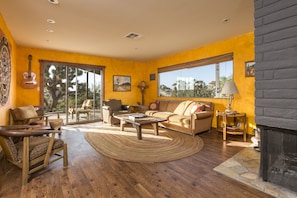 The Living Room, with wood fireplace, leads to the back porch.