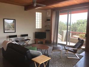 Living room with 10' high beam ceiling and fan with view balcony