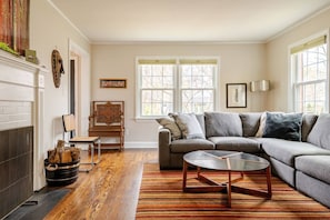 Living room with large couch, tv, games, books, and fireplace.