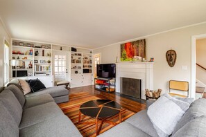 Living room with large couch, tv, games, books, and fireplace.