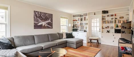 Living room with large couch, tv, games, books, and fireplace.