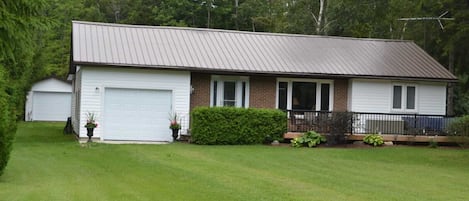 Front of the cottage includes large deck with seating area.