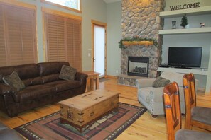 Floor to ceiling river rock fireplace, flat screen tv and entrance to patio.