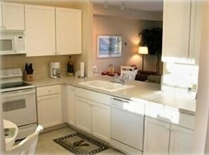 Kitchen with view of living room, counterspace and doorwall out to patio.