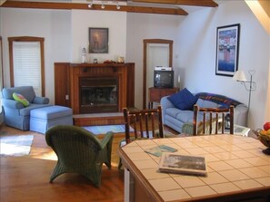 Living Room w/ gas fireplace, trac lighting, exposed wooden beams and skylights.