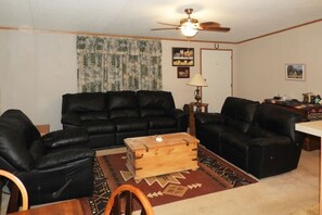 Living Room in the Ranch House with leather sofa, love seat, and chair. The "Bar Porch", a second living/dining area is through the door.