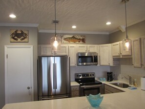 Kitchen with new appliances, cabinets, lighting, and quartz countertops.