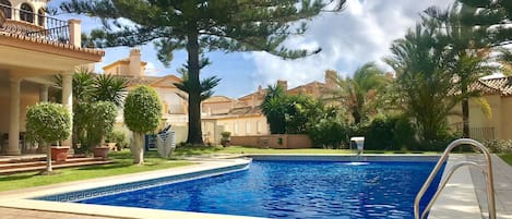 Gated swimming pool with sun beds arranged daily by maintenance.