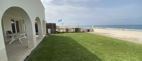 Casa a la izquierda y jardín con salida a la playa