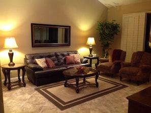 Well appointed living room with brand-new end tables, coffee table, couch and reclining chairs.