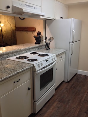 Updated galley kitchen featuring granite counter tops and wood look flooring.