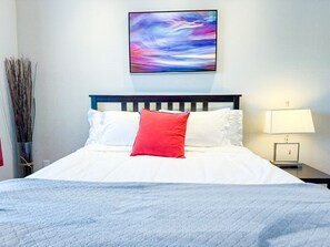 Main-level queen suite with crisp linens, calming coastal-inspired artwork, and a bold pop of color—your peaceful retreat after a day exploring Portland.