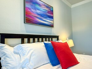 A pop of red and blue sets the tone for restful nights—drift off beneath vibrant artwork in this serene and stylish main-floor bedroom sanctuary.
