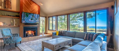 Living room with fireplace, breathtaking views & 65-inch smart television.