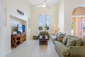 Plush green sofas, a soft tile floor, and breezy ceiling fan.