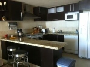 Full kitchen with granite countertops, gas stove and oven, side by side fridge 