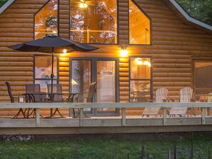 Twilight view of lighted cabin and deck