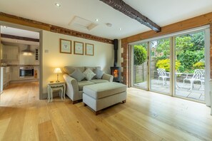 The Old Cow Shed, Pott Row: Sitting area with wood burning stove and bi-fold doors to courtyard garden
