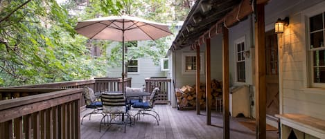 Deck above creek on front of house with outdoor dining table