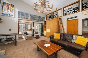 Living room with a variety of seating options, access to the balcony, skylight windows, and loft access.