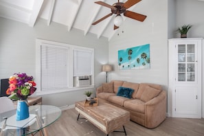 Living area includes window AC, ceiling fan, and TV.