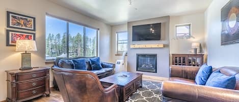 Living Area - Flat screen TV, fireplace, large windows, and natural lighting.