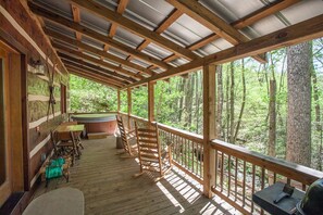 Grill, rocking chairs, hot tub and table for two overlooking the creek