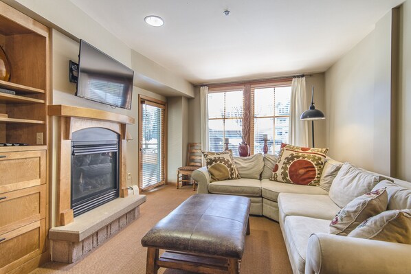 Living Area - Sectional sofa with Queen size sofa sleeper. Private balcony access, flat screen TV, and fireplace.
