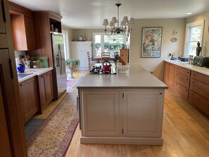 Huge kitchen with center island, farmhouse table, and opening to patio/lawn/pool