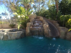 Swimming pool with slide, hot tub and waterfall features.