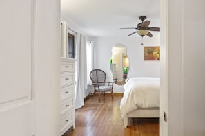 Bedroom has dresser storage, ceiling fan and a reading chair.