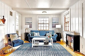 Living room w/ plenty of seating,  65” TV, Woodburning fireplace & small library