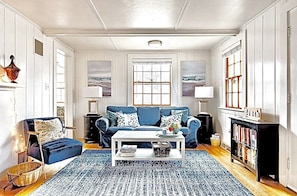 Living room w/ plenty of seating, 65” TV, Woodburning fireplace & small library