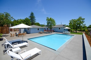 Pool patio with umbrella and chaise lounge chairs for relaxing poolside
