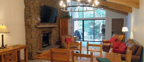 Living room with wood fireplace, dining table, and balcony w/ propane BBQ grill