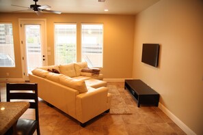 Living room with leather sectional couch, flat screen TV, and ceiling fan