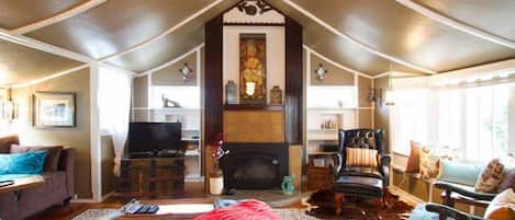 Spacious living room with tented cathedral ceiling and adorned fireplace