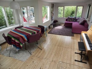 Living room with sofa bed, piano and dining table.