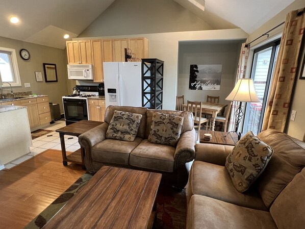 Living room with vaulted ceiling and open floor plan, HD TV, door to deck.