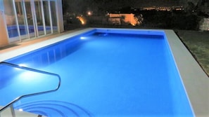 Amazing outside area at night with inviting swimming pool